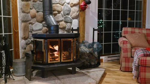 Wood stove fireplace with metal body and glass door in house with cozy interior
