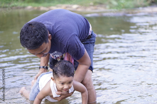 Little toddler boy stand in the water lake and making splash. looking for some fish concept.       