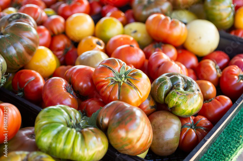A background of large heirloom tomatoes on display at a local farmers market.