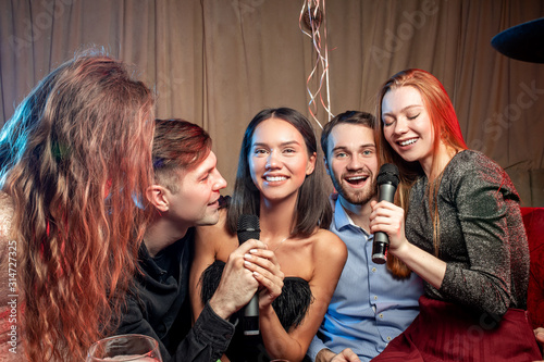 holiday, party,celebration concept. young people have cheerful pastime in karaoke, positive people together sing in microphone and have fun, chilling out