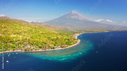 Panoramic view of the Jemeluk Bay, Amed village, the Agung volcano mountains and the azure sea in Bali, Indonesia. Aerial view 4K photo