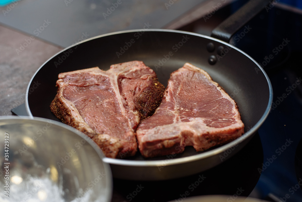 Raw Fresh Marbled Meat Beef on a grill pan ready for cooking. Man cooking beef steaks. a grill pan with beef steaks on kitchen Raw Fresh Marbled Meat Beef on a grill pan ready for cooking. Man cooking beef steaks. a grill pan with beef steaks on kitchen