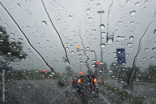 Rain drop falling on car windshield, drive car on street in city in heavy rain photo