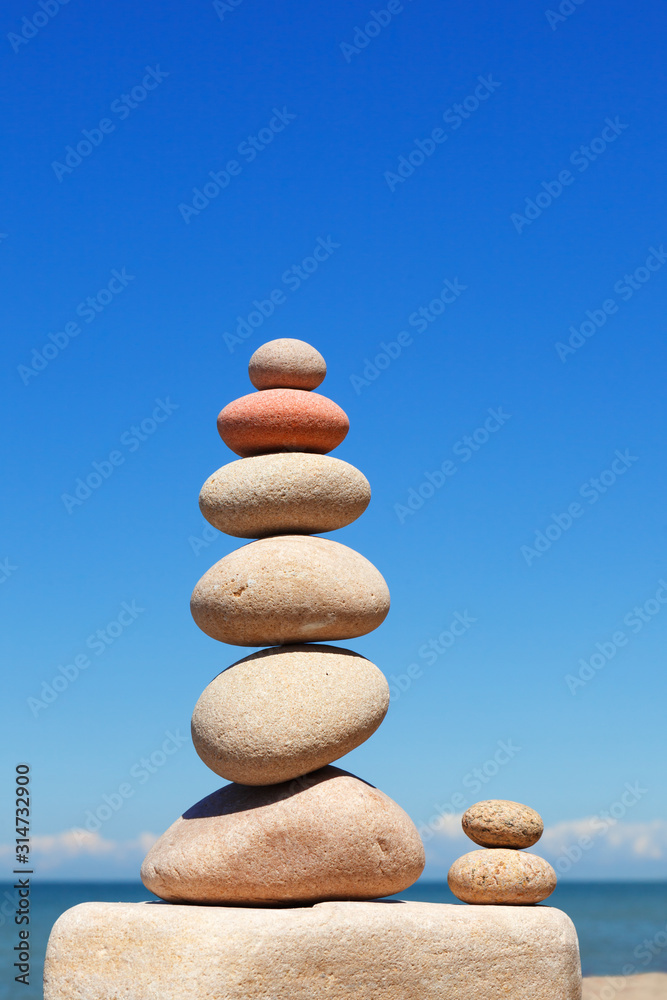High Rock zen pyramid of white and pink pebbles on a background of blue sky and sea. High Rock zen pyramid of white and pink pebbles on a background of blue sky and sea.