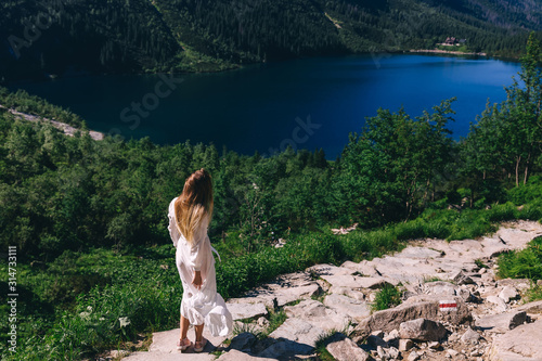 girl in a white dress is whirling. rocky shore of the lake. coni photo