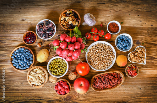 Healthy superfood eating variety collection in bowls: vegetables, fruits, berries, seeds, raw food, cereal, leaf vegetable on colorful background.