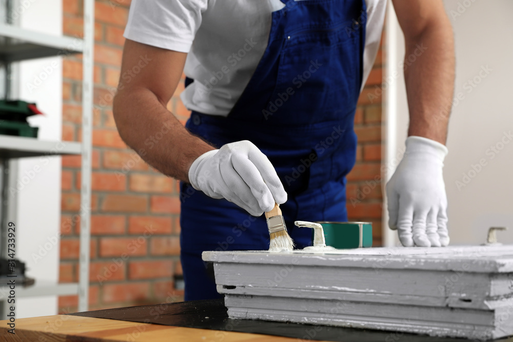 Repairman painting old window at table indoors, closeup Repairman painting old window at table indoors, closeup