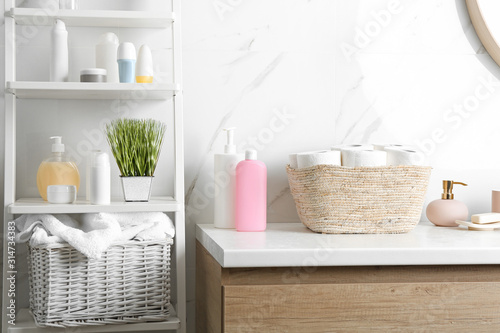Fotografie Wicker basket with toilet paper rolls on countertop in bathroom