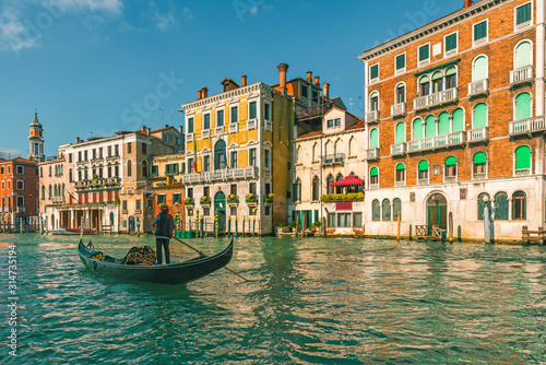 Fototapeta Naklejka Na Ścianę i Meble -  Venetian gondolier punting gondola through Grand Canal along colorful building facades in Venice