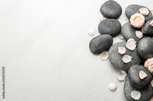 Stones and flowers on light background  top view with space for text. Zen lifestyle