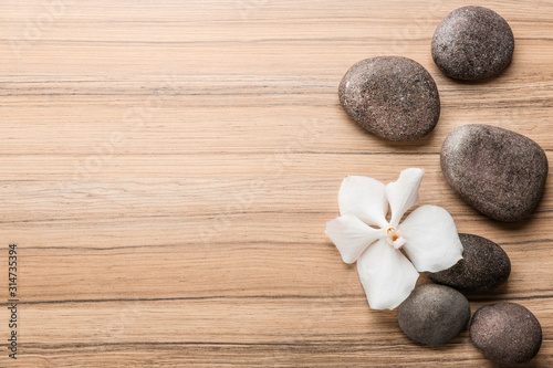 Stones and orchid flower on wooden background, top view with space for text. Zen lifestyle