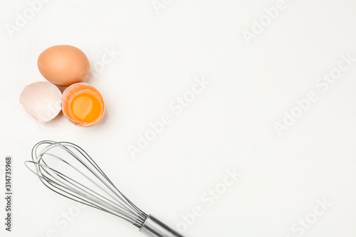 Raw eggs and whisk on white table, top view with space for text. Baking pie