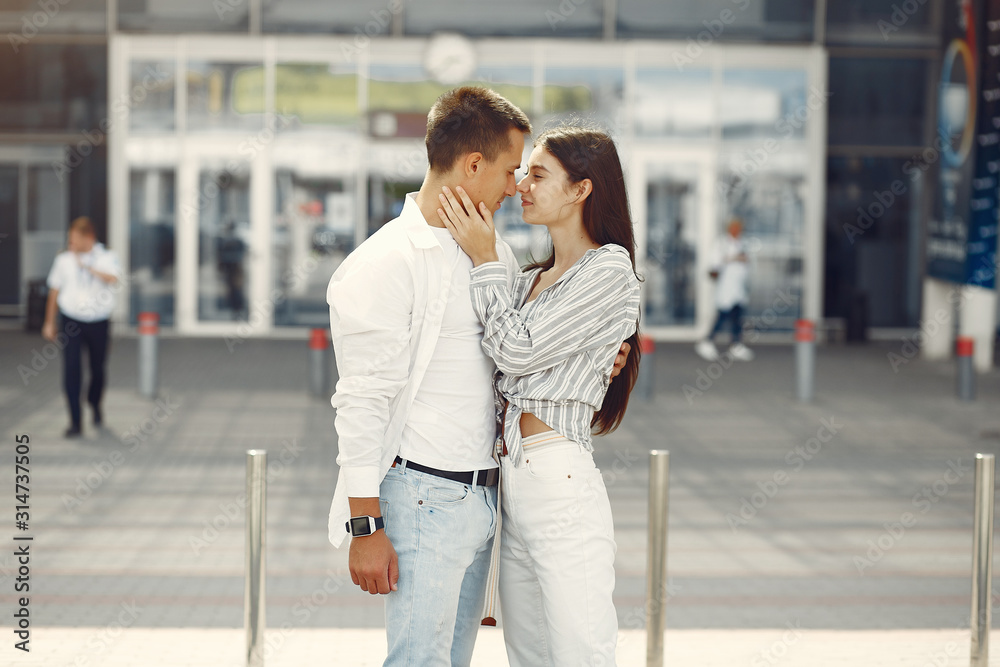 Couple in a airport. Beautiful brunette in a white shirt. Man in a white t-shirt