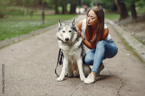 Beautiful girl in a white t-shirt. Woman in a summer park. Lady with a dog © hetmanstock2