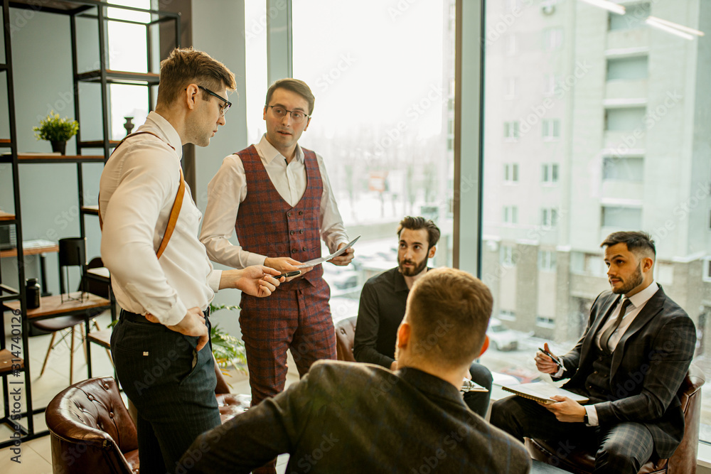 successful and confident caucasian men, business partners hold meeting in modern office. young men in formal wear discuss and planning strategies together, useful cooperation of leaders in boardroom successful and confident caucasian men, business partners hold meeting in modern office. young men in formal wear discuss and planning strategies together, useful cooperation of leaders in boardroom
