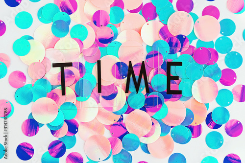 Background with shiny pink, purple and holographic sequins with word Time, abstract background.