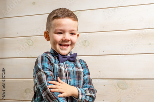 Foto A 4 years old boy in a blue clerical shirt is crying on a light wooden background