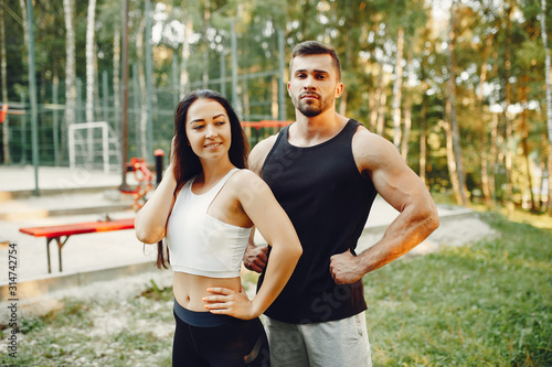 Couple training. Guy in a sports shorts. Girl in a summer park