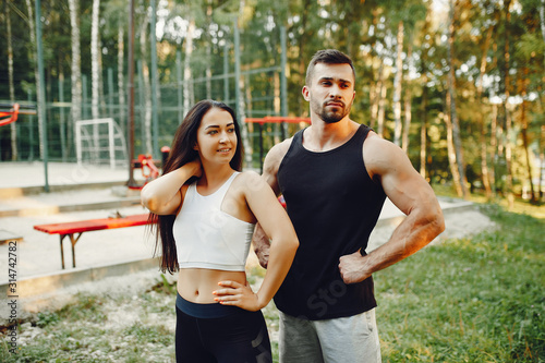 Couple training. Guy in a sports shorts. Girl in a summer park