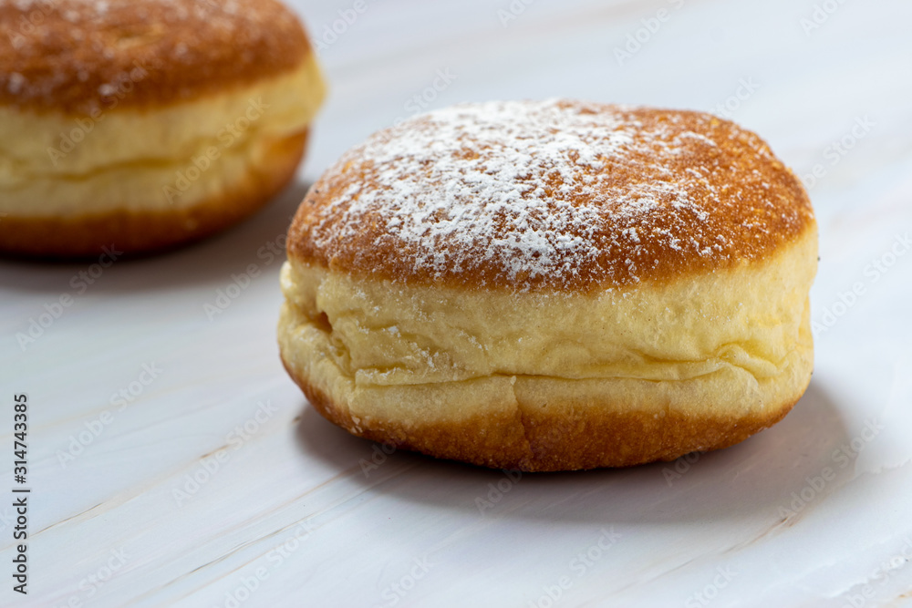 Two donuts in close-up, isolated on white marble backdrop. Filled with jam. Two donuts in close-up, isolated on white marble backdrop. Filled with jam.