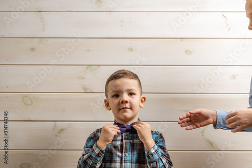 A 4-year-old boy in a blue klepy shirt cries on a light wooden background and his brother, 10 years old, is standing. photo