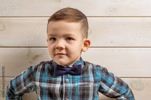 Bild auf Leinwand A 4 years old boy in a blue clerical shirt is crying on a light wooden background