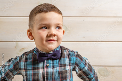 Foto A 4 years old boy in a blue clerical shirt is crying on a light wooden background