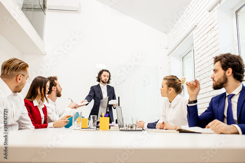 group of young caucasian business leaders gathered in office to discuss projects and ideas together, colleagues sit on table and have conversation. Business people concept