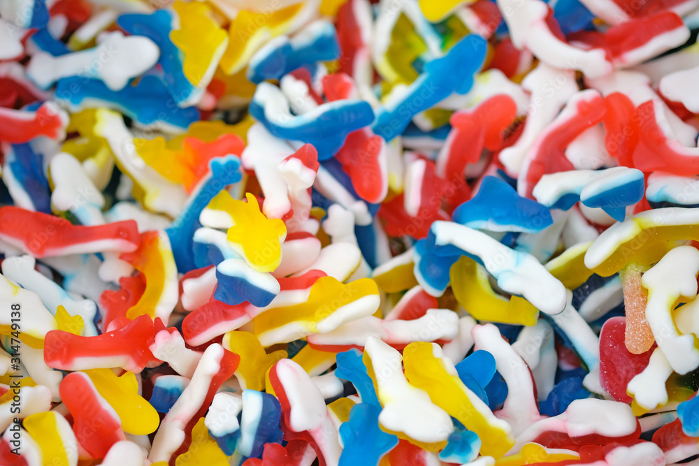 Fototapeta premium Colorful jelly sweets top view. Delicious marmalade. Candy in the form of fish blue, yellow and red, background.