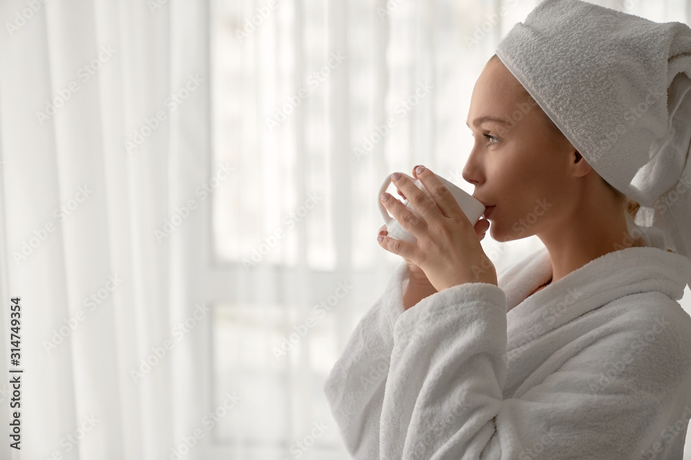 Girl in bathrobe drinking cup of coffee. - obrazy, fototapety, plakaty 
