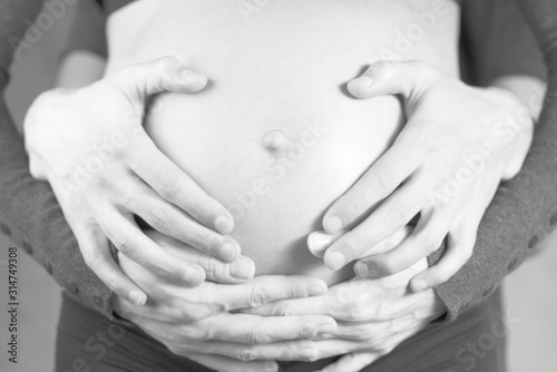 male and female hands on the belly of a pregnant woman
