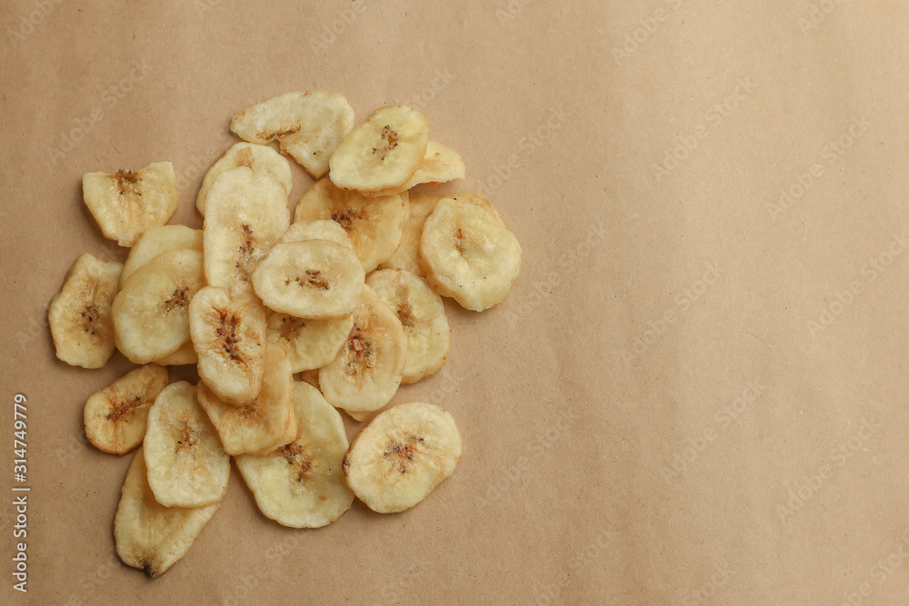 Fototapeta premium Tasty banana chips on brown background