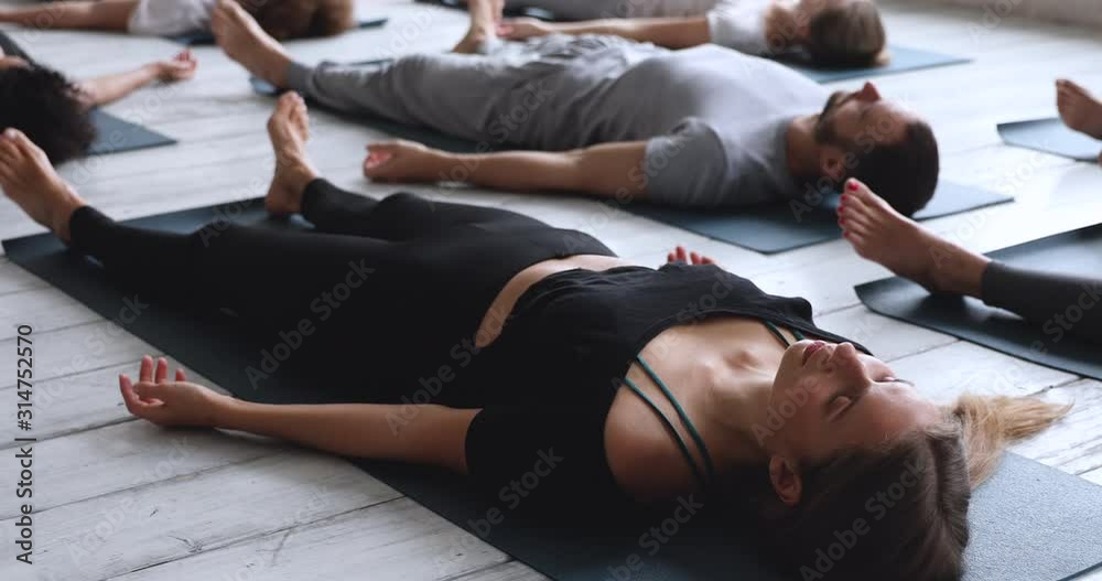 Caucasian woman with multi-ethnic people practicing Savasana