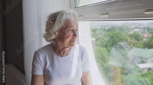 Senior woman sitting on windowsill.