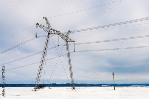 High voltage electric pillar against blue sky. Winter landscape.