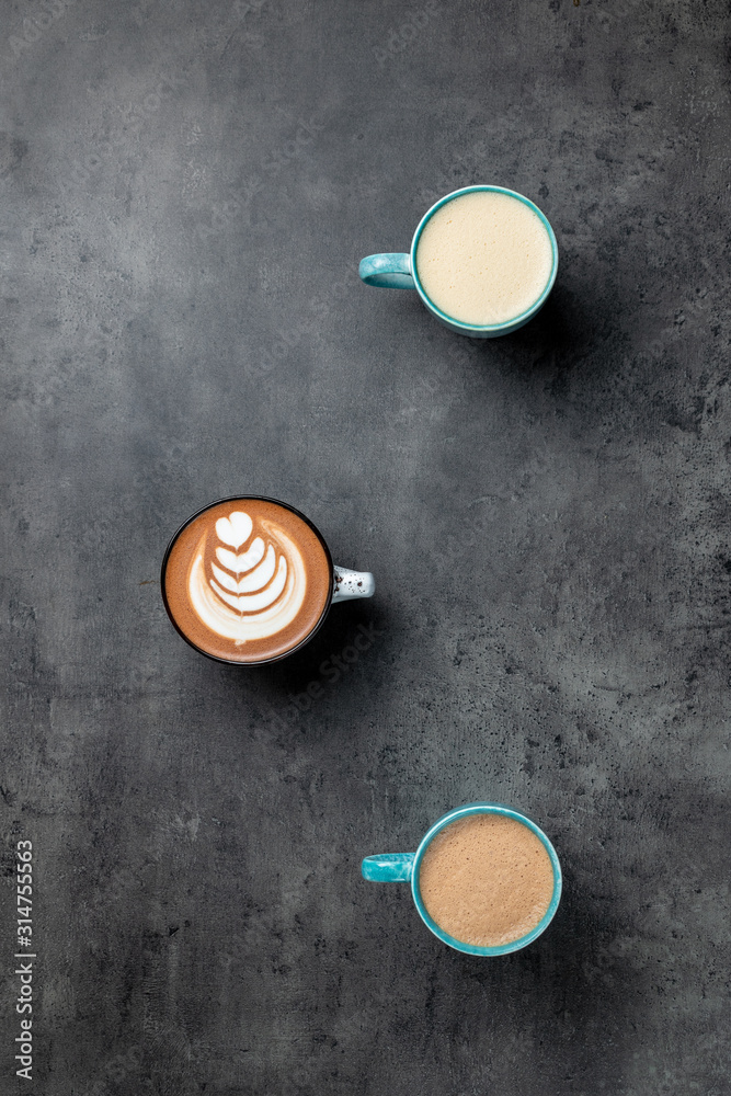 3 cups of coffee on grey background with negative space top view