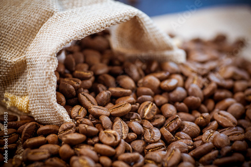 Cafe beans get enough sleep from their bag on a sackcloth background. Black coffee beans close-up. Roasted coffee beans background.