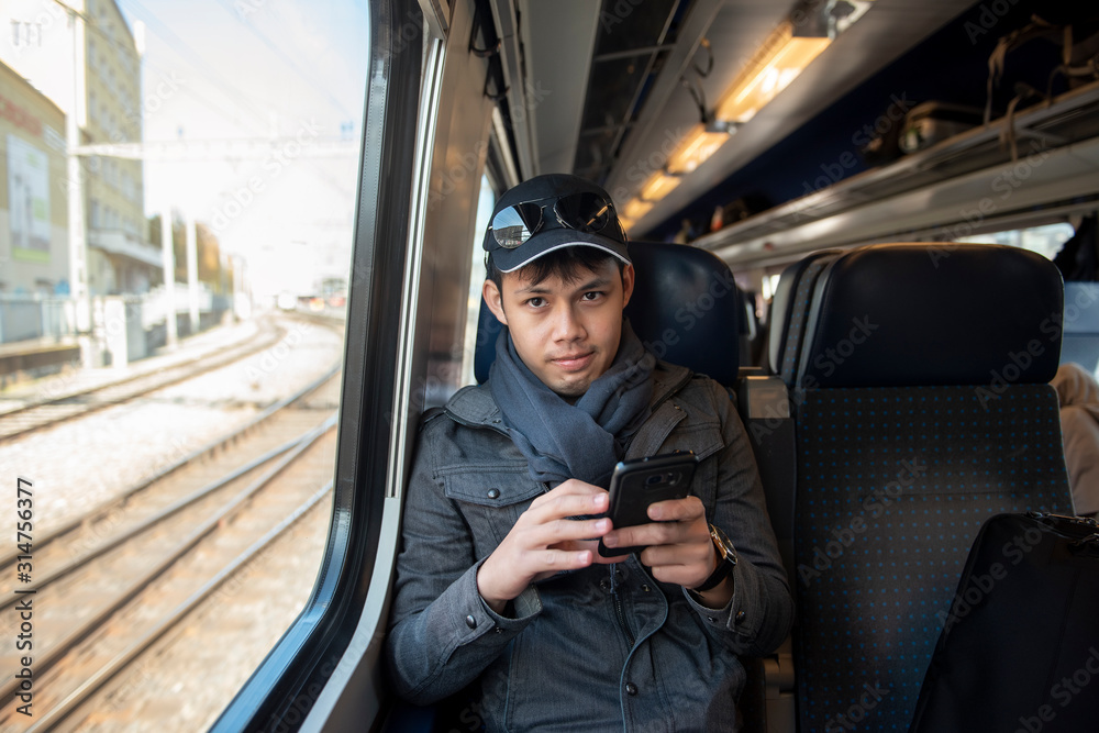 An Asian man traveling by railway in Europe