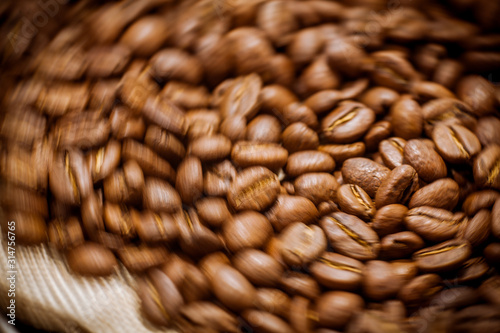 Black coffee beans close-up. Roasted coffee beans background. Brown coffee beans isolated on burlap background.