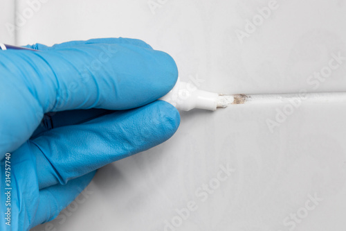 Obraz na plátně Man wearing gloves using grout pen on ceramic wall tiles to restore white grout
