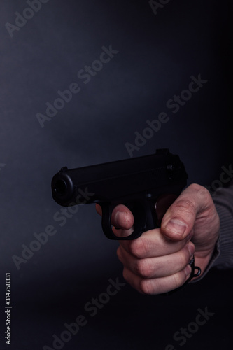 Male hand with gun isolated on black background. Man with a gun ready to shoot, focus on the weapon.