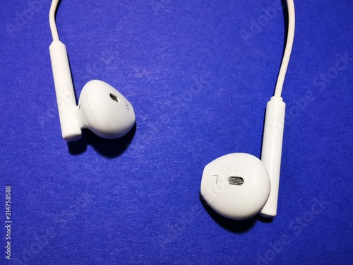 White headphones for a smartphone or an MP3 player with loud and quiet switch on blue background