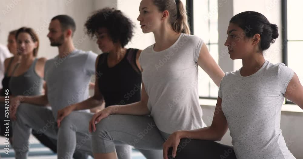 Indian ethnicity woman with other people practising yoga exercise indoors Indian ethnicity woman with other people practising yoga exercise indoors
