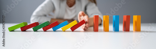 Businessperson Hand Stopping Colorful Blocks From Falling photo