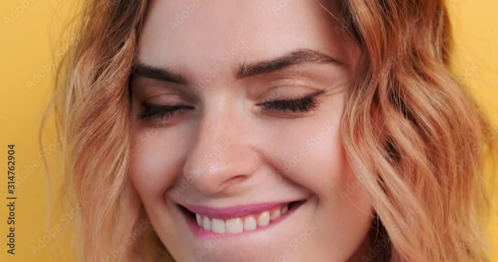 Happy young woman licks lips with tongue sexually smiles closeup portrait looking at camera on isolated yellow background. Bright full lips with bright pink lipstick. Emotions of people. Lifestyle. Happy young woman licks lips with tongue sexually smiles closeup portrait looking at camera on isolated yellow background. Bright full lips with bright pink lipstick. Emotions of people. Lifestyle.