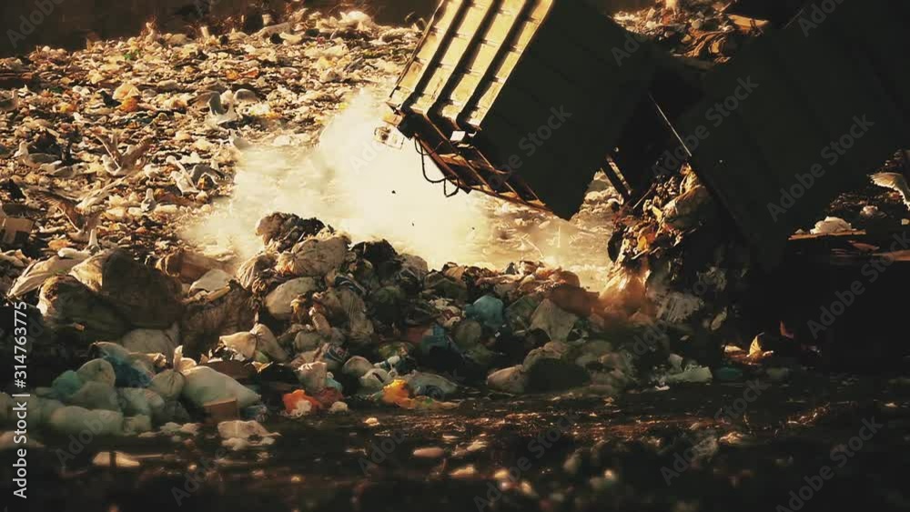 Waste densely lay. Trash truck spills garbage at sunset. Dust and dirt. Landfill. Environmental pollution in slow motion.