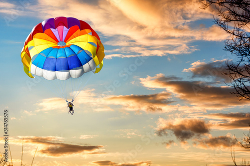 A man is gliding with a parachute on the background of sunset. photo