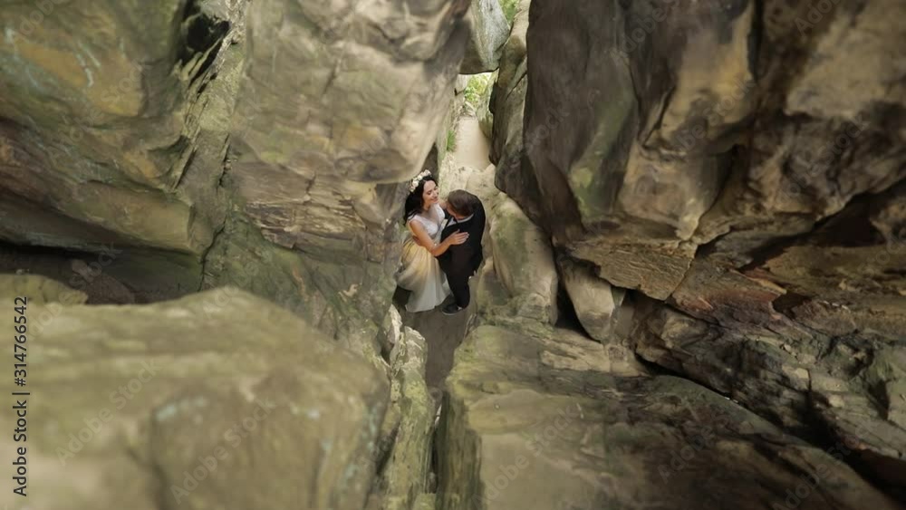 Groom with bride standing in cave of mountain hills. Wedding couple in love Groom with bride standing in cave of mountain hills. Wedding couple in love