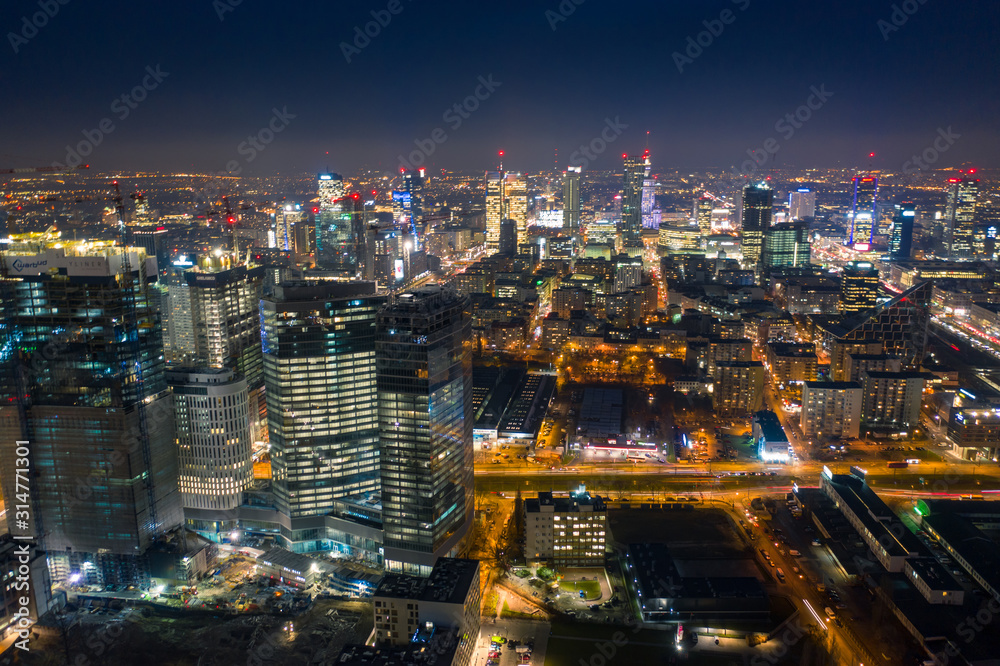 Fototapeta premium Warsaw-Poland 04. December. 2019. Aerial view of luminous high-rise buildings of the business center with lighted windows located in Warsaw against the evening sky. 