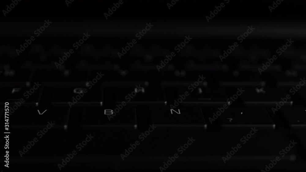 illuminated keyboard buttons letters in RGB colors on modern black laptop